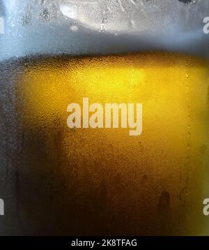 Glass of frothy craft beer in a cold beer mug Stock Photo