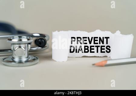 Medical concept. On a gray background, a stethoscope, a pencil and a paper plate with the inscription - PREVENT DIABETES Stock Photo