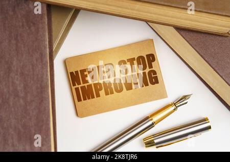 Education and business concept. Next to the books lies a pen and a sign with the inscription - Never stop improving Stock Photo