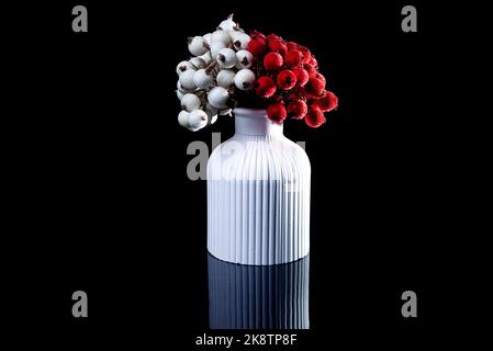 A close up shot of white and red berries in ice in a white vase. The porcelain vase has fluted surface. The vase with a bunch is isolated against the Stock Photo