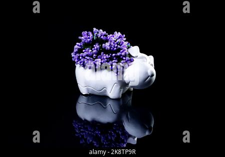 A close up shot of ceramic vase in the form of a dog with flowers The porcelain vase has fluted surface. The vase with a bunch is isolated against the Stock Photo