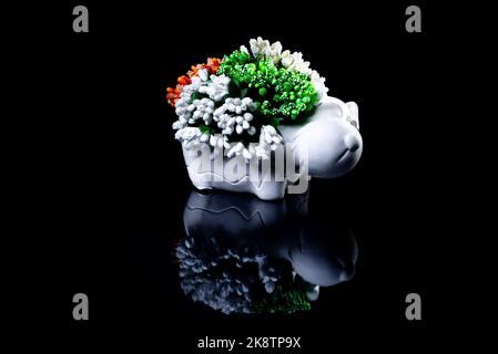 A close up shot of ceramic vase in the form of a dog with flowers The porcelain vase has fluted surface. The vase with a bunch is isolated against the Stock Photo