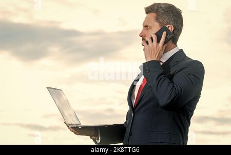 businessman in suit speaking on phone and hold laptop Stock Photo