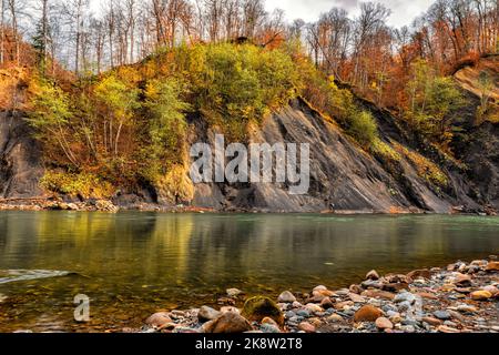Beautiful autumn landscape of the river flowing at the foot of the mountains with steep banks Stock Photo
