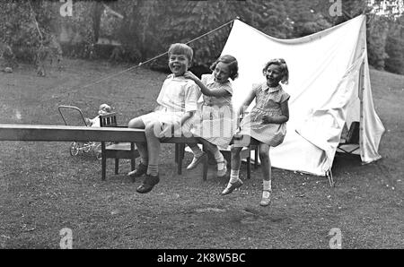 Skaugum June 1937. Princess Ragnhild (in the middle) and Princess Astrid play in the garden at Skaugum, along with an unidentified boy. The three together, sitting on a domp hined in the garden. A white tent in the background. Photo: NTB / NTB Stock Photo