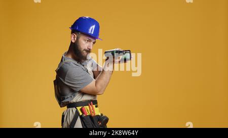 Portrait of repairman builder using electric power drill machine to work on renovation and refurbishment. Engineer mechanic working with drilling nail gun on industrial repair. Stock Photo