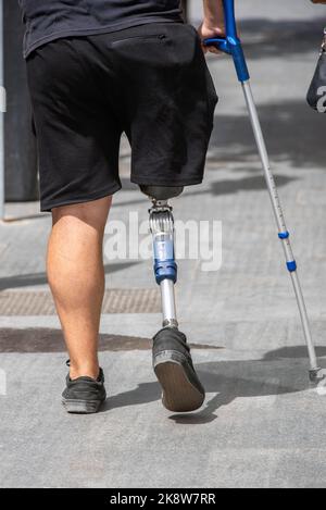 person walking on the street with a prosthetic leg Stock Photo