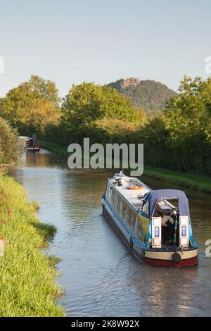 Narrowboats Navigating the Shropshire Union Canal in Cheshire on a Sunny Autumn Evening in Sight of the Rocky Crag of Beeston Castle Stock Photo