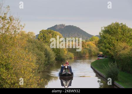 A Narrowboat in Evening Sunshine on the Shropshire Union Canal In Front of the Rocky Crags of Beeston Castle in Cheshire Stock Photo