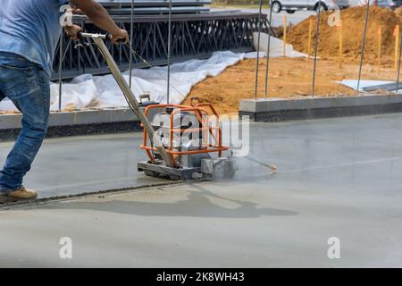 Worker using cutting machine are cutting concrete for expansion isolation joint of foundation concrete after pouring in construction site Stock Photo