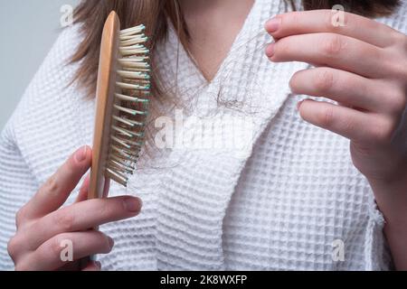 Hair loss in women. Young woman is upset because of hair loss. Problem hair in comb. Stock Photo