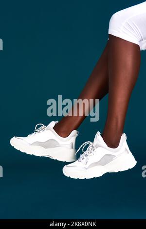New sneakers gives me new motivation. an unrecognizable sportswoman wearing her sneakers before working out against a dark background in the studio. Stock Photo