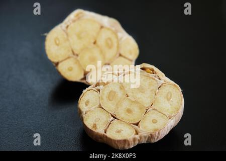 Head of garlic is cut lengthwise lies on black background Stock Photo