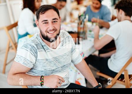 You cant use up creativity. Cropped portrait of a handsome young man sitting with his friends during an art class in the studio. Stock Photo