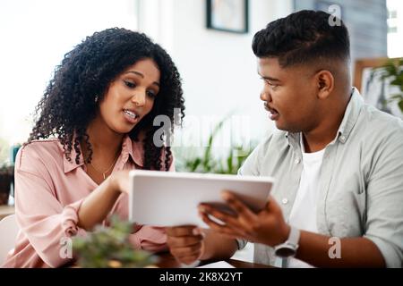 With wireless tech productivity happens anywhere. a young businessman and businesswoman using a digital tablet in a modern office. Stock Photo