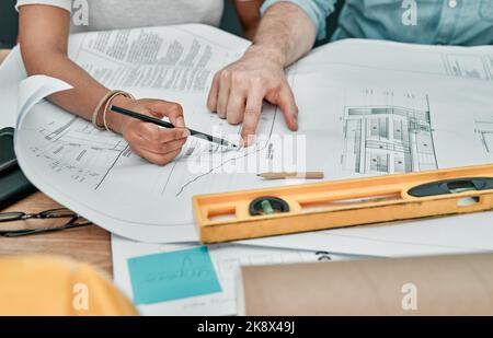 Finishing up a few blueprints. Closeup shot of two architects working with blueprints in an office. Stock Photo