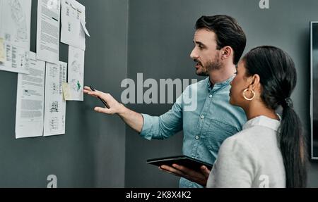 Teamwork leads to great success. two architects working with blueprints on a wall in an office. Stock Photo