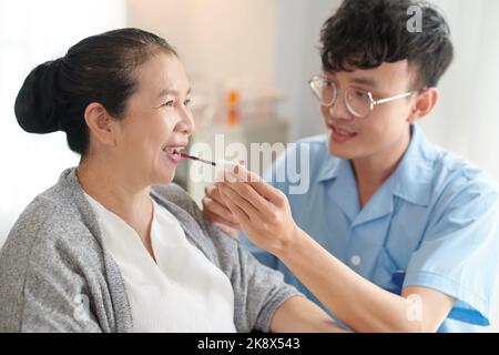 Nursing home worker helping senior woman to apply liquid lipstick before date with her boyfriend Stock Photo