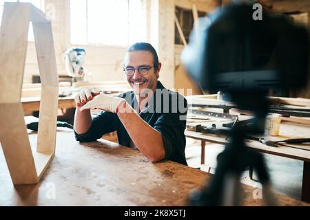 The feedback on my carpentry vlog has been amazing. Portrait of young carpenter recording a tutorial of him making a wooden masterpiece on a video Stock Photo