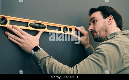 Every detail has to be perfect. a young architect holding a spirit-level against a wall. Stock Photo