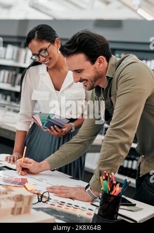 This came out so well. two aspiring young architects smiling while working together in a modern office. Stock Photo