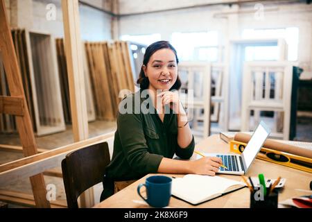 I build dreams with wood. a female carpenter using a laptop in her workshop. Stock Photo