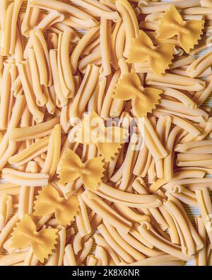 Close-up pattern of raw pasta with casarecce and farfalle on top Stock Photo