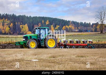 Farmer ploughing stubble field with John Deere 7530 tractor and plough on a day of autumn. Salo, Finland. October 13, 2022. Stock Photo