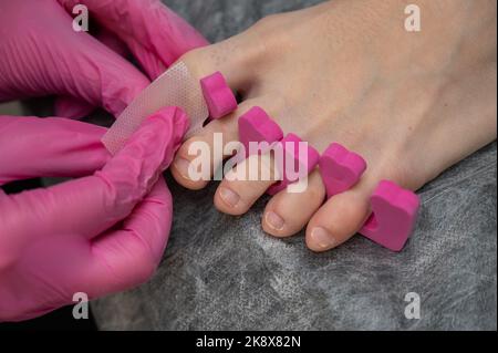 A manicurist degreases the toenails of a client in a beauty salon. Stock Photo