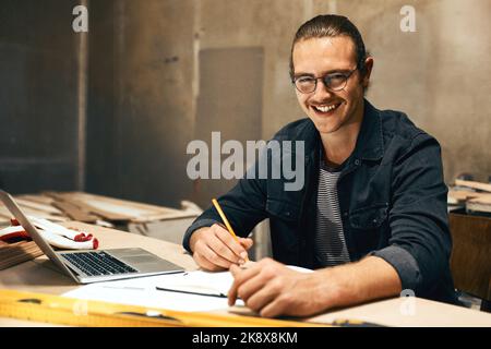 Always happy to work hard. Portrait of a focused young male carpenter working on a project inside of a workshop at night. Stock Photo