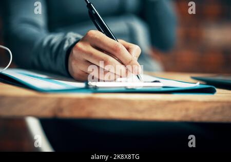 I make notes of everything. an unrecognizable woman making notes at her desk. Stock Photo