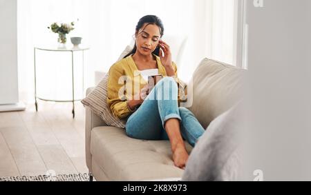 Does this look right. an attractive young businesswoman sitting on her couch and using her cellphone while at home. Stock Photo
