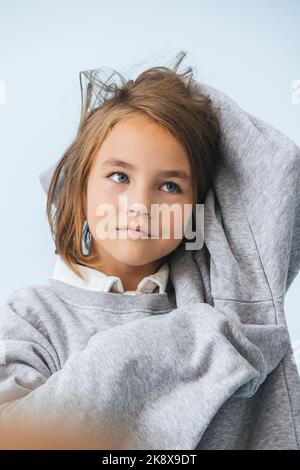 Dreamy eight year old girl in oversize hoodie looking up. Stock Photo