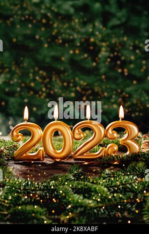 Holiday background Happy New Year 2023. Numbers of year 2023 made by gold burning candles on bokeh festive sparkling background. celebrating New Year Stock Photo