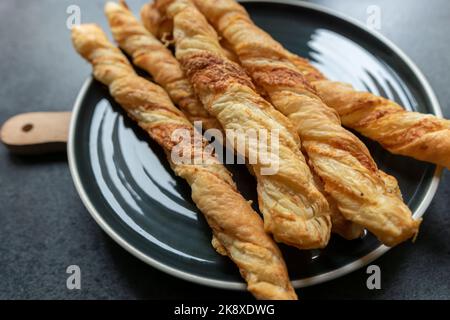 freshly baked, crispy, puff sticks on a round black plate. Perfect for a party. Stock Photo