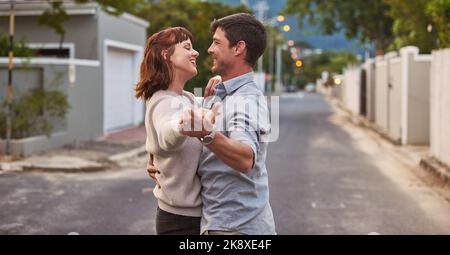 Were dancing our way to happiness. an affectionate young couple dancing together on the street. Stock Photo
