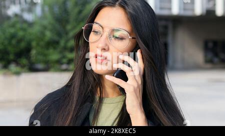 Close-up of a Latin business woman with glasses talking on the cell phone. Stock Photo