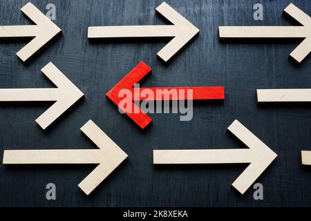 Arrows in one direction and red in the opposite. On contrary, be against the trend concept. Stock Photo