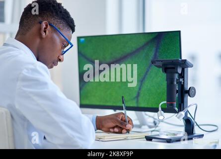 Doing a whole lot of research. a focused young male scientist making notes while conducting experiments inside of a laboratory. Stock Photo