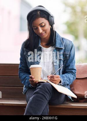 Coffee helps me to stay focused. a young woman making notes while sitting outdoors. Stock Photo