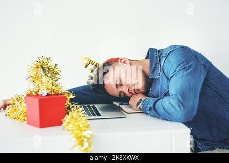 Working over the festive season is such a drag. a handsome young businessman sleeping on his desk while working in his office on Christmas Eve. Stock Photo