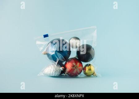 Various Christmas decorations packed in a plastic zip bag on blue background. Minimal holiday greeting concept. Stock Photo