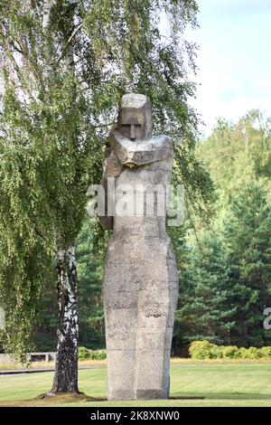 A vertical view of a weeping woman monument made of stone in the greenery of Salaspils memorials Stock Photo