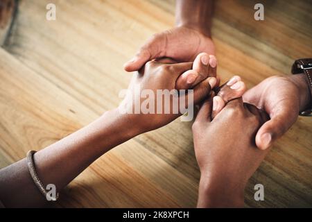 Hand in hand through it all. an unrecognizable couple holding hands on a table at home. Stock Photo