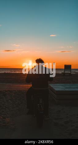 A silhouette of a man watching scenic sunset over the Atlantic ocean in ...