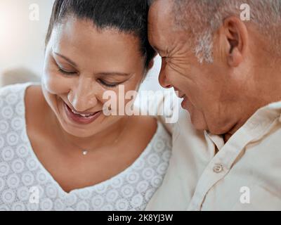 Love, family and face of elderly couple embrace, relax and smile while bonding and sharing a romantic moment in their home. Senior, man and woman Stock Photo
