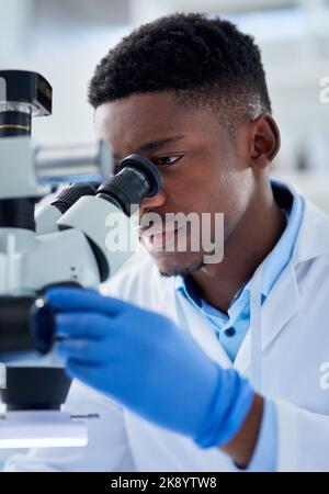 There is so much to see here. a focused young male scientist looking at test samples through a microscope inside of a laboratory during the day. Stock Photo