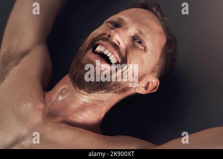 The gym is my happy place. a handsome young man smiling and feeling cheerful after working out indoors. Stock Photo