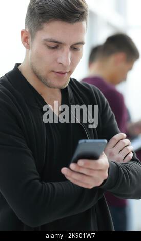 smiling young man reading a message on his smartphone. Stock Photo