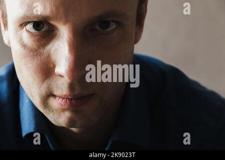 Young serious European man looks at the camera, close up studio face portrait with selective soft focus Stock Photo